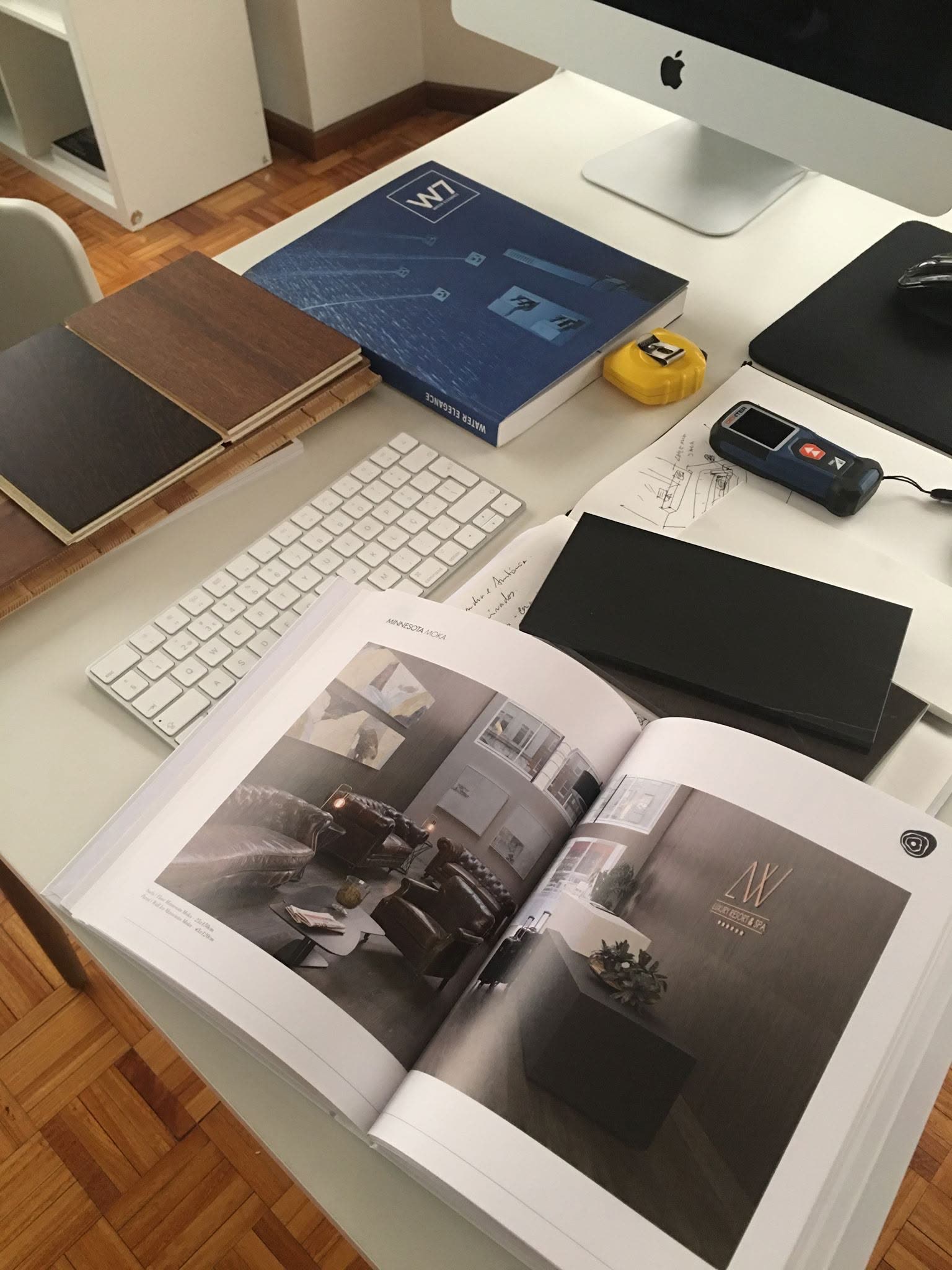 Secretária de trabalho com computador, livro e amostras de material