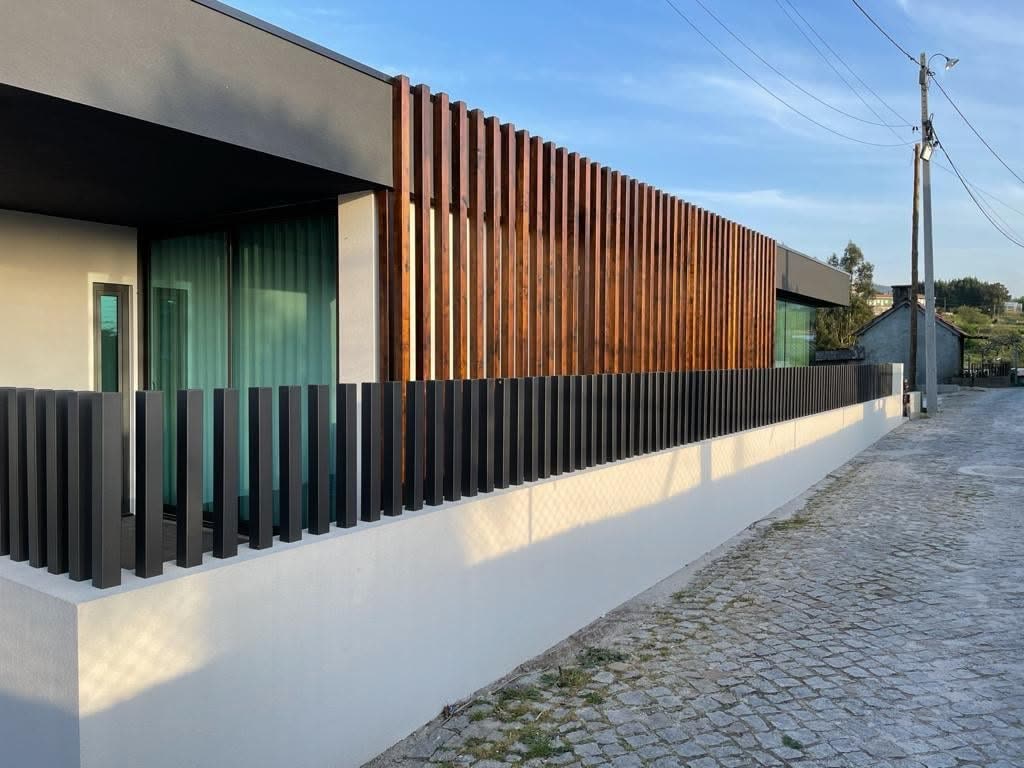 Muro branco encimado por ripado escuro ao longo da rua